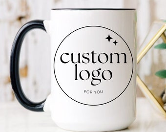 May include: White ceramic mug with a black handle and a black rim. The mug has a black circle with the text "custom logo" and the words "for you" underneath.