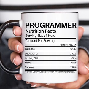 May include: White ceramic coffee mug with a black handle. The mug has a black outline and the text "PROGRAMMER Nutrition Facts Serving Size: 1 Nerd Amount Per Serving %Daily Value* Patience 500% Debugging 230% Coding Skill 100% Sleep 100% Caffeine 270% *Percent Daily Values are based on programming language."