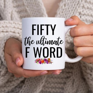 May include: White ceramic mug with black text that reads "FIFTY the ultimate F WORD" with a floral design at the bottom.