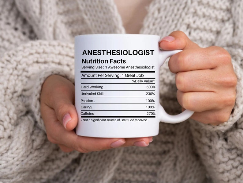 May include: White ceramic coffee mug with a black and white graphic of a nutrition facts label for an anesthesiologist. The label lists the daily value of hard working, unrivaled skill, passion, caring, and caffeine.