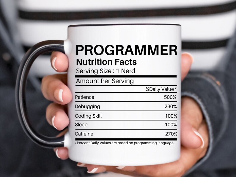 May include: White ceramic coffee mug with a black handle. The mug has a black outline and the text "PROGRAMMER Nutrition Facts Serving Size: 1 Nerd Amount Per Serving %Daily Value* Patience 500% Debugging 230% Coding Skill 100% Sleep 100% Caffeine 270% *Percent Daily Values are based on programming language."