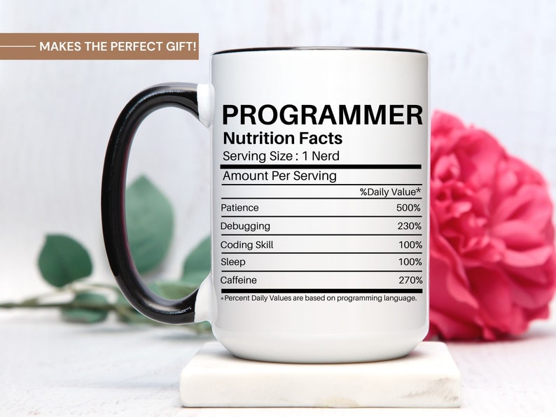 May include: White ceramic mug with a black handle. The mug has a black rim and features a graphic of a nutrition facts label for a "Programmer". The label lists the daily value of patience, debugging, coding skill, sleep, and caffeine.