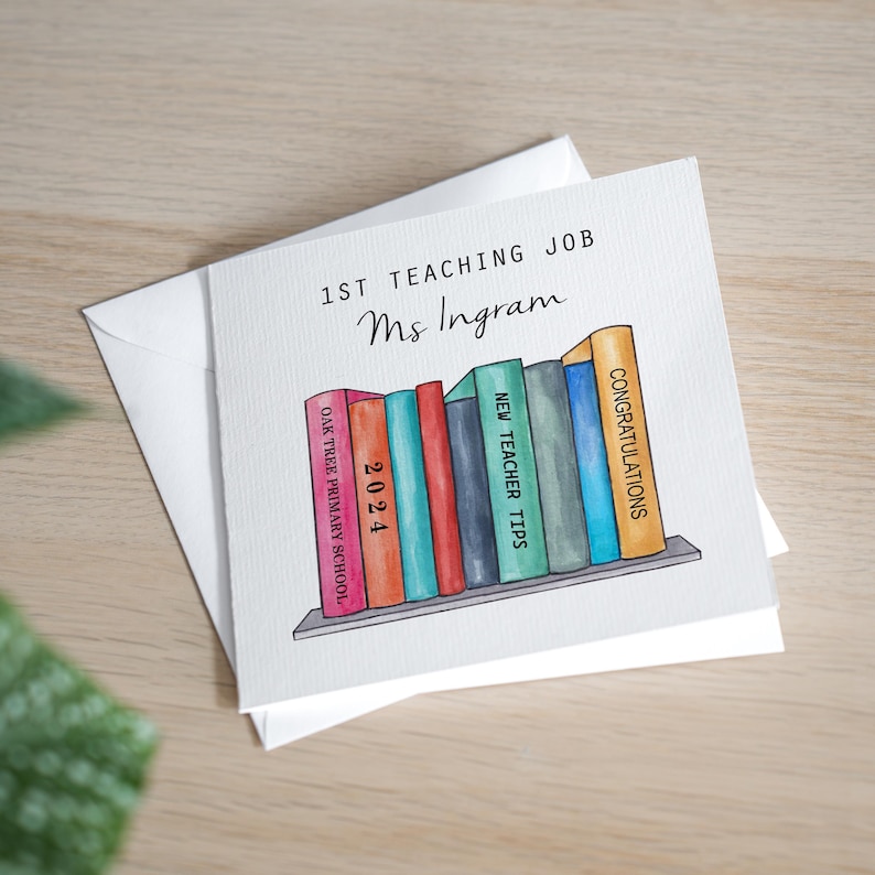 May include: A white card with the text "1st Teaching Job Ms Ingram" and a watercolor illustration of a bookshelf with colorful books. The book titles are "Oak Tree Primary School", "2024", "New Teacher Tips", and "Congratulations".