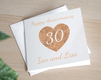 May include: A white card with a copper-colored heart with the number 30 inside. The text "Happy Anniversary" is at the top of the card and "Ian and Lisa" is at the bottom.