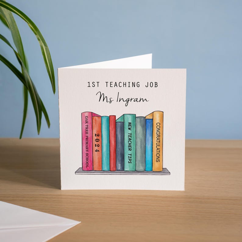 May include: A card with a watercolor illustration of a bookshelf with books. The books have titles like "Congratulations", "New Teacher Tips", and "2024". The card says "1st Teaching Job Ms. Ingram" at the top.