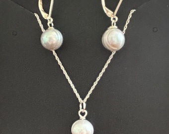 May include: A silver necklace and earrings set with a single pearl pendant and matching pearl drop earrings.