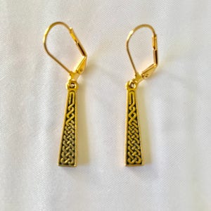 May include: A pair of gold dangle earrings featuring a Celtic knot design. The earrings have a simple hook fastening.
