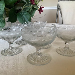May include: Set of six clear glass dessert cups with a delicate etched floral design. The cups have a wide bowl and a tall, slender stem.