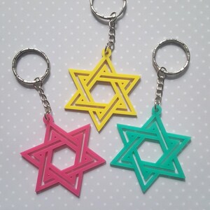 May include: Three Star of David keychains in yellow, pink, and teal. Each keychain features a six-pointed star with a smaller star inside.