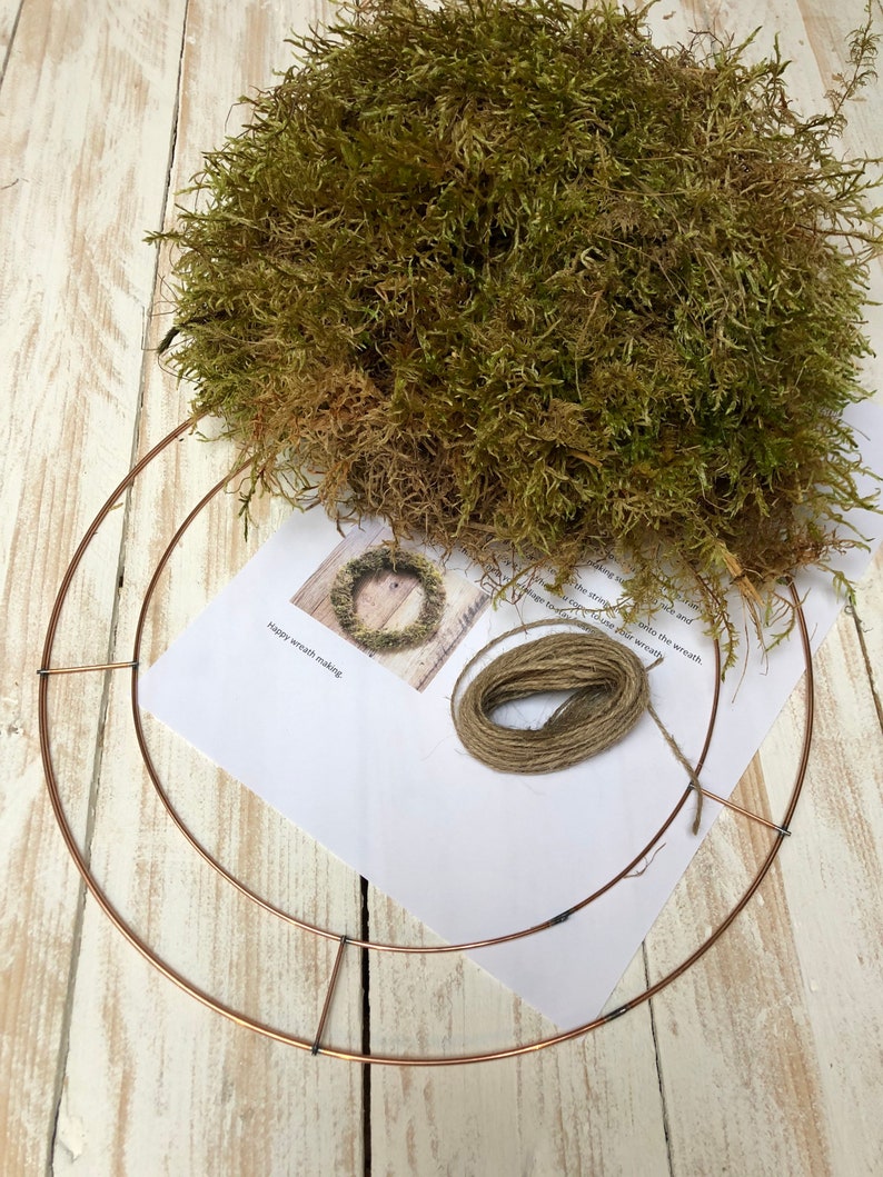 Pu&ograve; includere: Un kit fai-da-te per la creazione di ghirlande con un telaio in metallo color rame, un fascio di muschio verde, spago e una guida stampata. La guida include il testo "Happy wreath making."