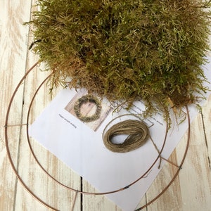 Pu&ograve; includere: Un kit fai-da-te per la creazione di ghirlande con un telaio in metallo color rame, muschio secco, spago e una guida stampata. Il muschio &egrave; un mix di verde e marrone. Il kit &egrave; su un fondo di legno bianco.