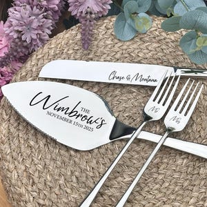 May include: A silver wedding cake knife and server set with the text "The Wimbrow's November 15th 2025" and "Chase & Montana". Two forks are engraved with "Mr" and "Mrs". The set is displayed on a woven surface with floral accents.