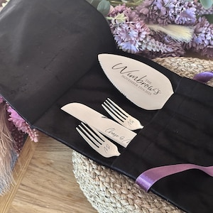May include: A silver cake server and two forks and knives set, engraved with names and a date, are displayed in a black case. The cake server is inscribed with "The Wimbrow's November 15th 2025". The set is tied with a purple ribbon.