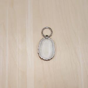 May include: A white antler keychain with a silver ring. The antler is smooth and polished.