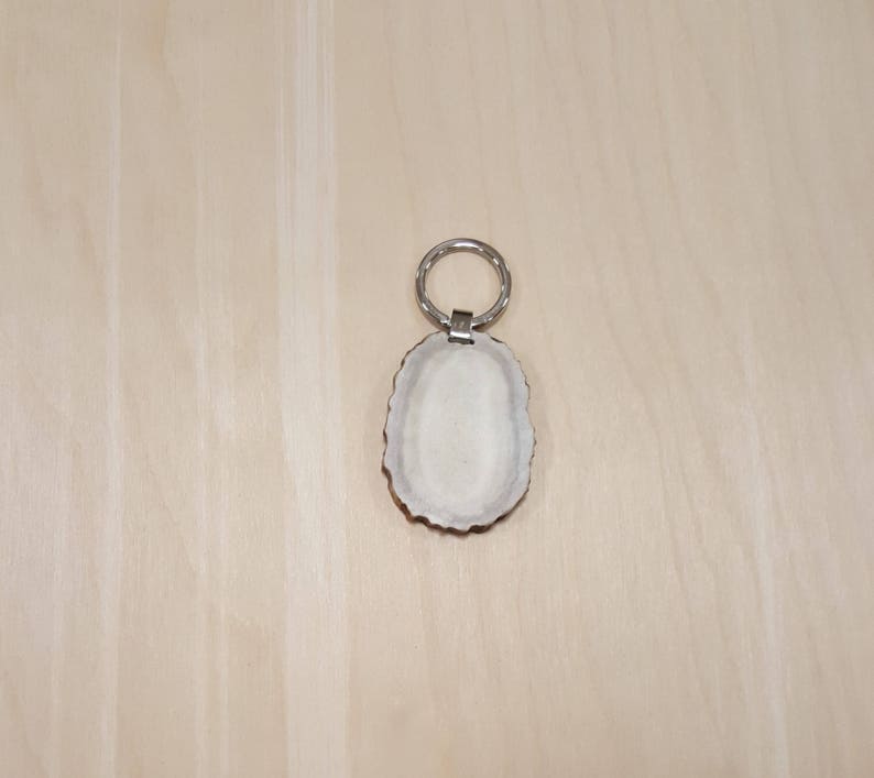 May include: A white antler keychain with a silver ring. The antler is smooth and polished.