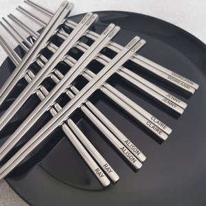 May include: A set of silver chopsticks with names engraved on each chopstick. The names include Martin, Marty, Crossy, Doireann, Jenny, Claire, Alison, and Ray.