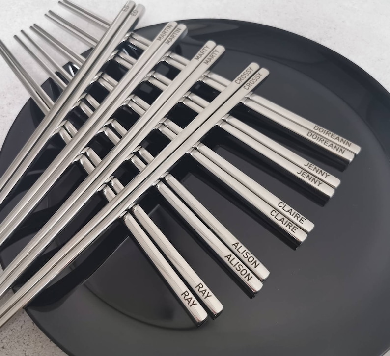 May include: A set of silver chopsticks with names engraved on each chopstick. The names include Martin, Marty, Crossy, Doireann, Jenny, Claire, Alison, and Ray.