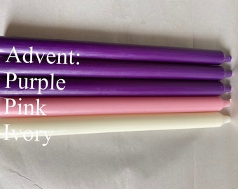 May include: Four taper candles in shades of purple, pink, and ivory. The text "Advent: Purple Pink Ivory" is displayed on the image. These candles are likely for a religious or decorative purpose.