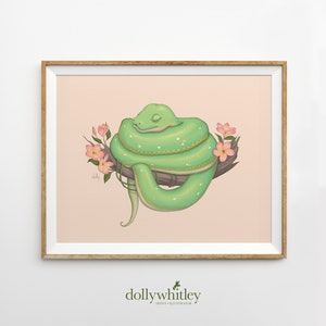 May include: A framed art print depicting a green snake coiled around a branch, with pink flowers and a light pink background. The snake has yellow spots and is smiling with its eyes closed. The artist's name, "dollywhitley", is at the bottom.
