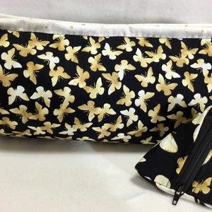 May include: A black fabric zippered pouch with a gold butterfly print and a smaller matching pouch with a zipper.