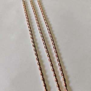 Puede incluir: Tres cucharas de bar de color cobre con un diseño de tallo retorcido. Las cucharas están dispuestas en diagonal sobre un fondo blanco. El diseño retorcido añade un elemento decorativo a las herramientas de bar.