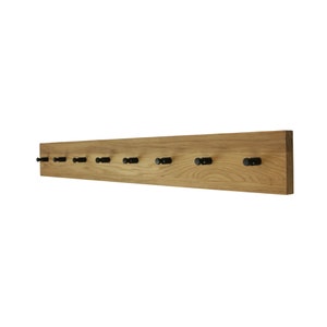 Könnte beinhalten: Ein Holz-Kleiderständer mit 10 schwarzen Metallhaken. Der Kleiderständer ist aus Naturholz gefertigt und hat einen rustikalen Look.
