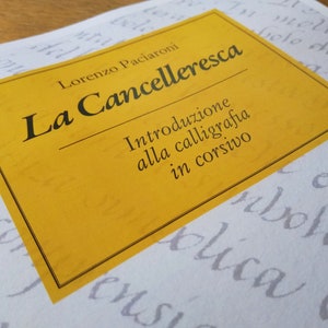 Può includere: Una copertina di libro gialla con il titolo "La Cancelleresca" in testo nero. Il sottotitolo è "Introduzione alla calligrafia in corsivo" in testo nero più piccolo.