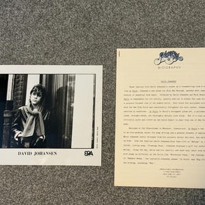 May include: Black and white photo of a young man with dark hair wearing a scarf and jacket. The photo is titled "David Johansen" and has a logo in the bottom left corner. The text "Biography" is at the top of a separate sheet of paper with a logo in the top left corner.