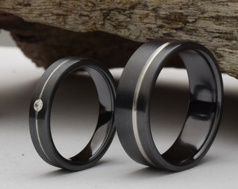 Wedding band set. Two black titanium rings with stone and offset groove