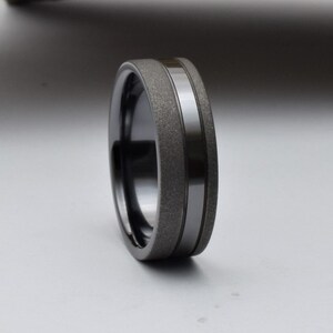 May include: A black and gray wedding band with a textured finish and a polished silver band.
