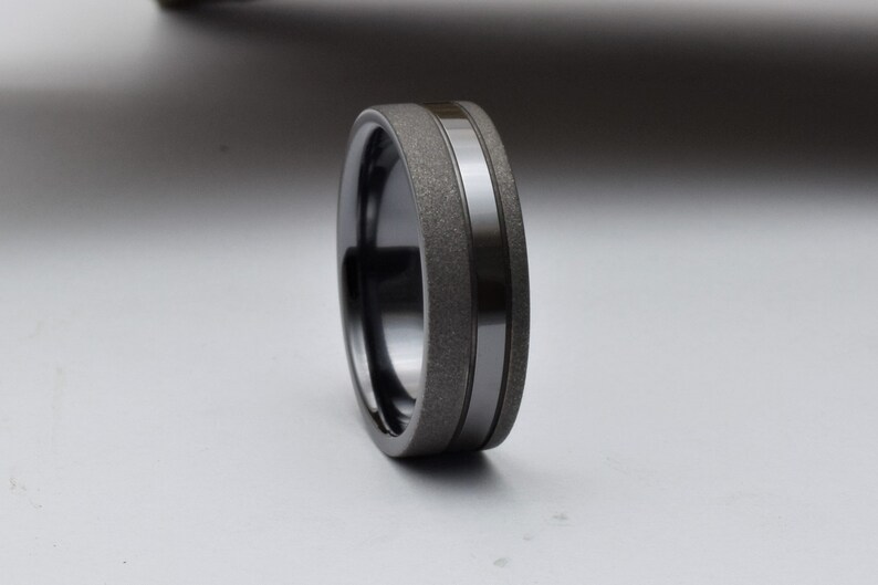 May include: A black and gray wedding band with a textured finish and a polished silver band.