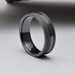 May include: A black and gray wedding band with a brushed finish and a polished groove.