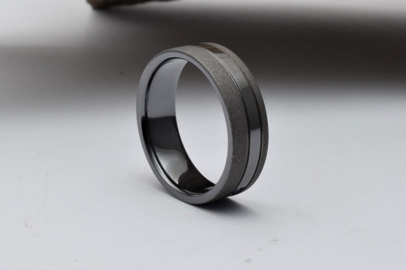 May include: A black and gray wedding band with a brushed finish and a polished groove.
