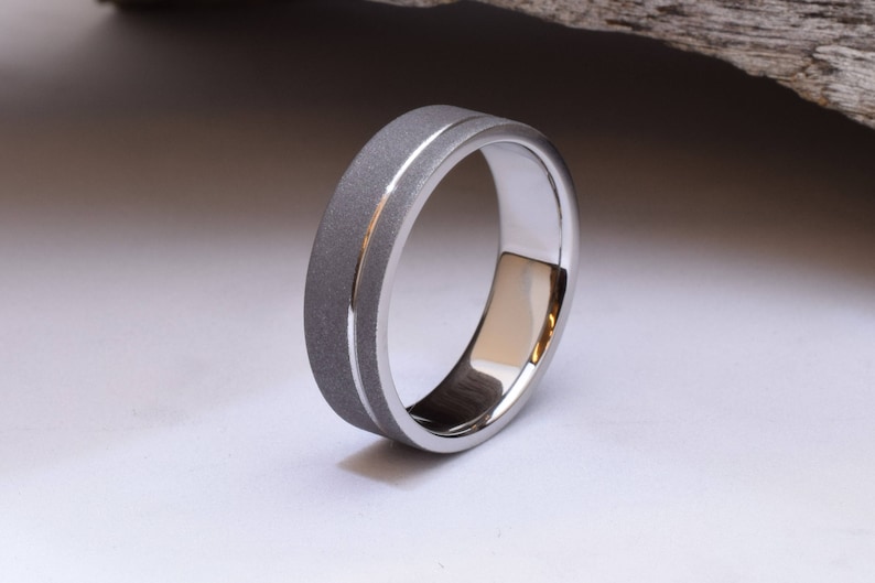 May include: A silver wedding band with a brushed finish and a polished edge.