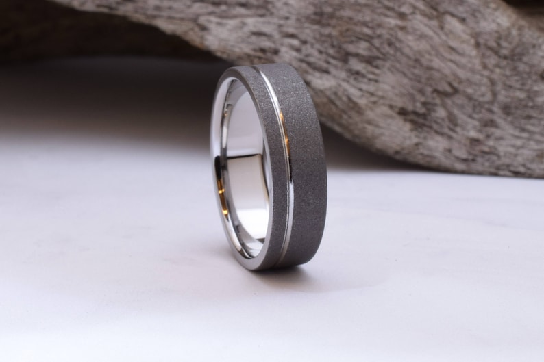 May include: A silver wedding band with a brushed finish and a polished groove.