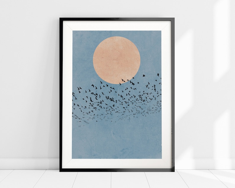 Pu&ograve; includere: Una stampa d'arte minimalista che presenta uno stormo di uccelli neri che volano in formazione contro un cielo blu con un grande cerchio arancione pallido al centro.