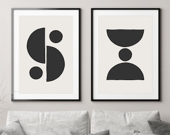 May include: Two black and white abstract art prints in black frames. The print on the left features a geometric design of circles and half circles. The print on the right features a geometric design of a half circle, a circle, and a half circle.