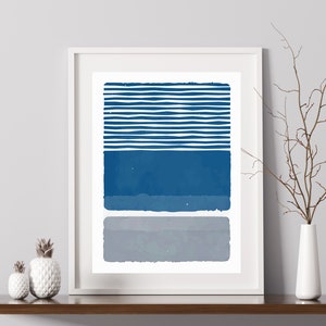 May include: A framed abstract print with a blue and gray geometric design. The print features a series of horizontal stripes in blue, followed by a solid blue rectangle, and a solid gray rectangle.