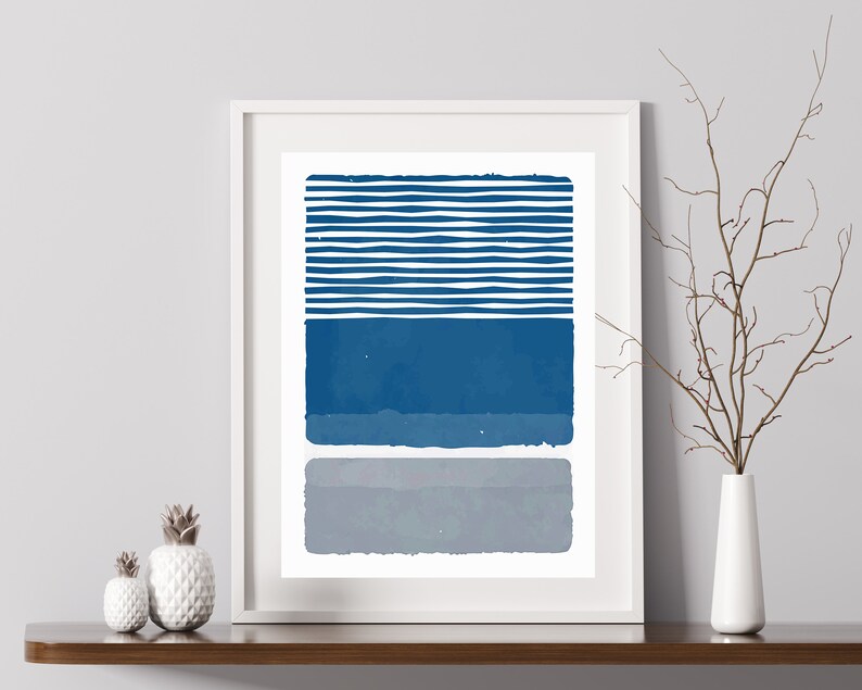 May include: A framed abstract print with a blue and gray geometric design. The print features a series of horizontal stripes in blue, followed by a solid blue rectangle, and a solid gray rectangle.
