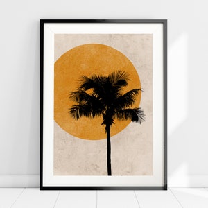K&ouml;nnte beinhalten: Gerahmter Kunstdruck mit einer schwarzen Silhouette einer Palme vor einem gro&szlig;en orangefarbenen Kreis auf strukturiertem beigefarbenem Hintergrund. Das Kunstwerk ist in einem schwarzen Rahmen und lehnt an einer wei&szlig;en Wand.