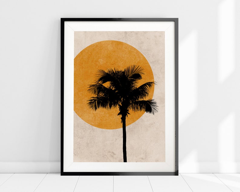 K&ouml;nnte beinhalten: Gerahmter Kunstdruck mit einer schwarzen Silhouette einer Palme vor einem gro&szlig;en orangefarbenen Kreis auf strukturiertem beigefarbenem Hintergrund. Das Kunstwerk ist in einem schwarzen Rahmen und lehnt an einer wei&szlig;en Wand.