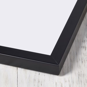 May include: Close-up of the corner of a black picture frame. The frame is made of wood and has a smooth finish.