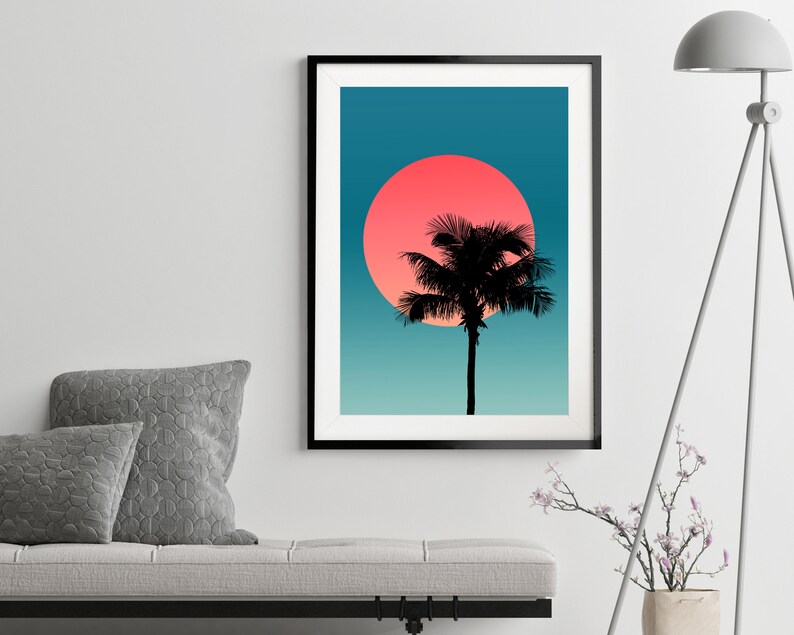 Pode incluir: Uma silhueta preta de uma palmeira fica em frente a um grande sol rosa e laranja contra um fundo degrad&ecirc; azul e verde.