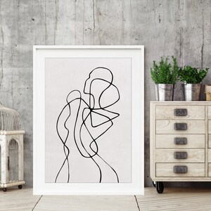 May include: A black and white abstract line drawing in a white frame on a gray concrete wall. The drawing is of a person's body.