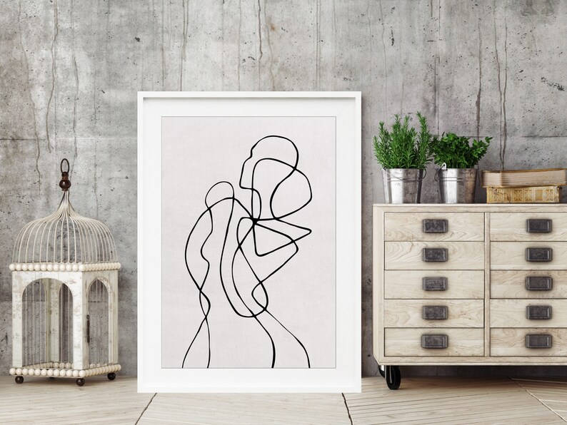 May include: A black and white abstract line drawing in a white frame on a gray concrete wall. The drawing is of a person's body.