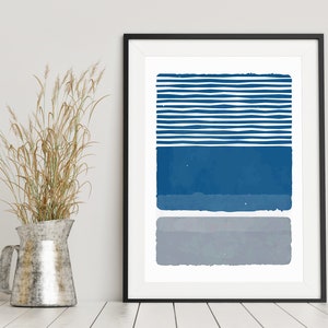 May include: A framed abstract print with a blue and gray color scheme. The print features a series of horizontal stripes in blue, followed by a solid blue rectangle, and a solid gray rectangle.