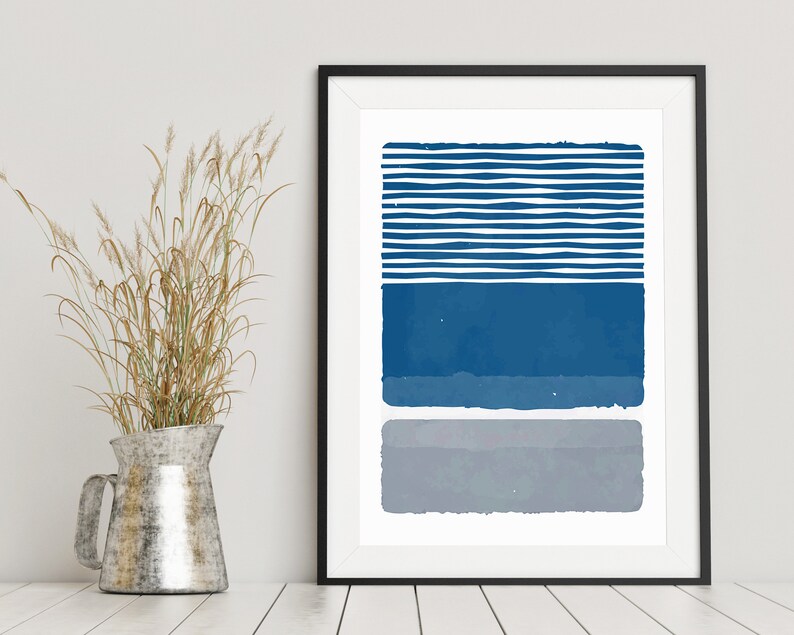 May include: A framed abstract print with a blue and gray color scheme. The print features a series of horizontal stripes in blue, followed by a solid blue rectangle, and a solid gray rectangle.