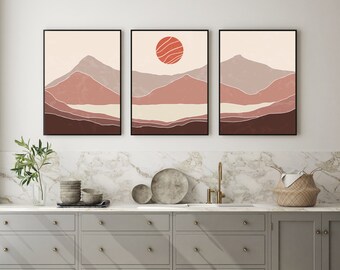 May include: Three abstract landscape prints with a minimalist design. Each print features a mountain range with a red sun in the top center of the middle print.