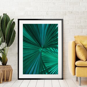 Op de afbeelding: Een ingelijste print van een close-up van een groen palmblad. Het blad is scherp en de achtergrond is wazig.