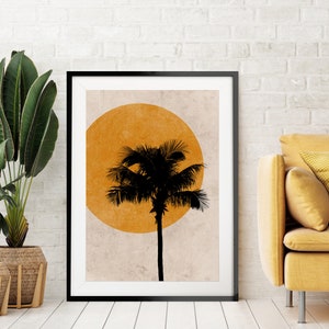 K&ouml;nnte beinhalten: Schwarz gerahmter Kunstdruck mit einer Palmensilhouette vor einer gro&szlig;en orangefarbenen Sonne. Das Kunstwerk wird in einem modernen Wohnzimmer mit einem gelben Sofa und Topfpflanzen pr&auml;sentiert. Der Kunstdruck verleiht eine tropische Note.